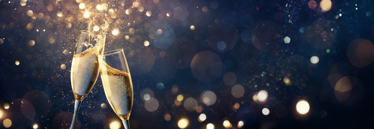 Célébration des toasts au champagne - Bonne année - Flûtes avec paillettes dorées sur fond abstrait bleu avec lumières bokeh défocalisées